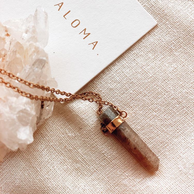 Saypaloma crystal necklace next to a label