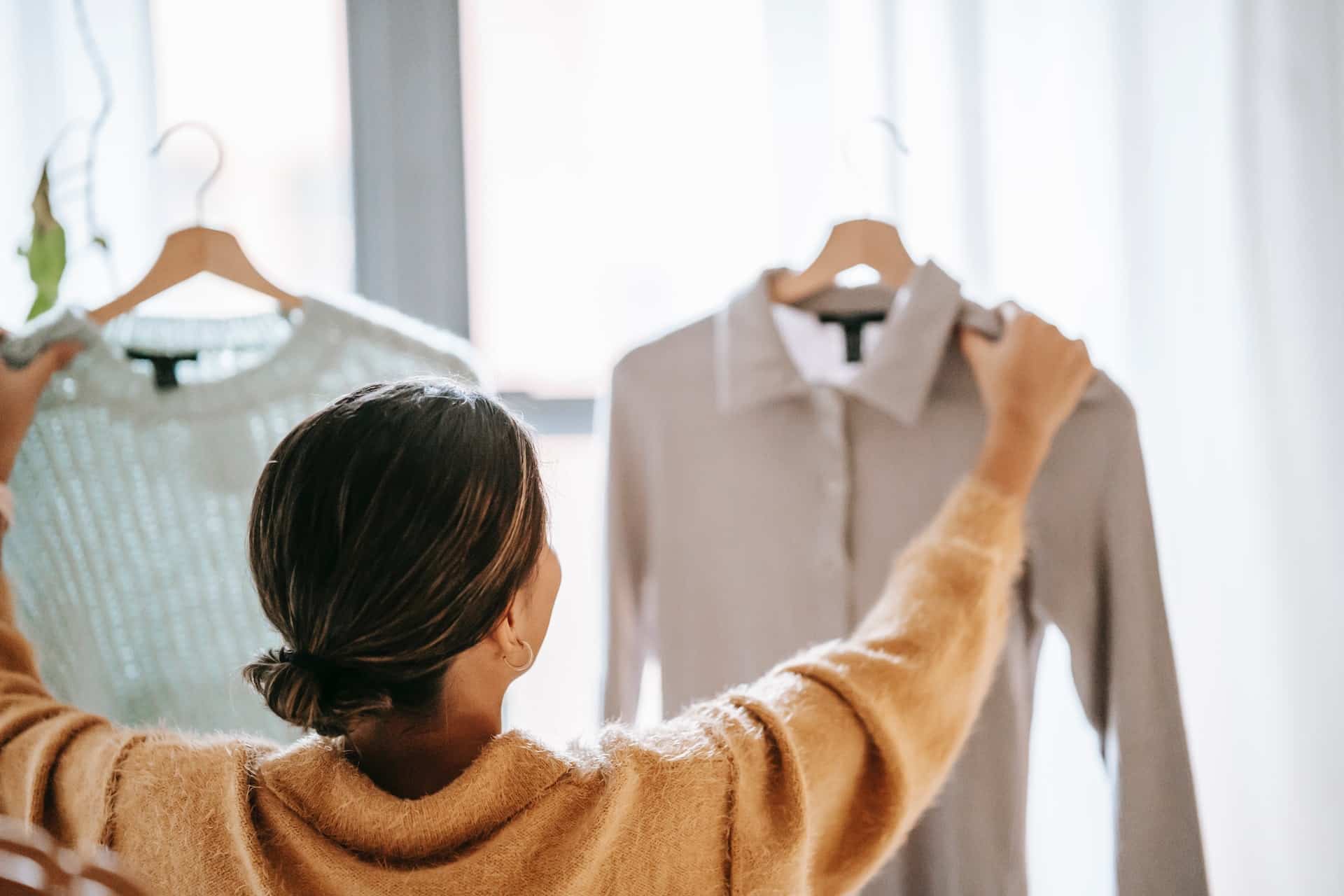 A woman looking at clothes on a hanger.