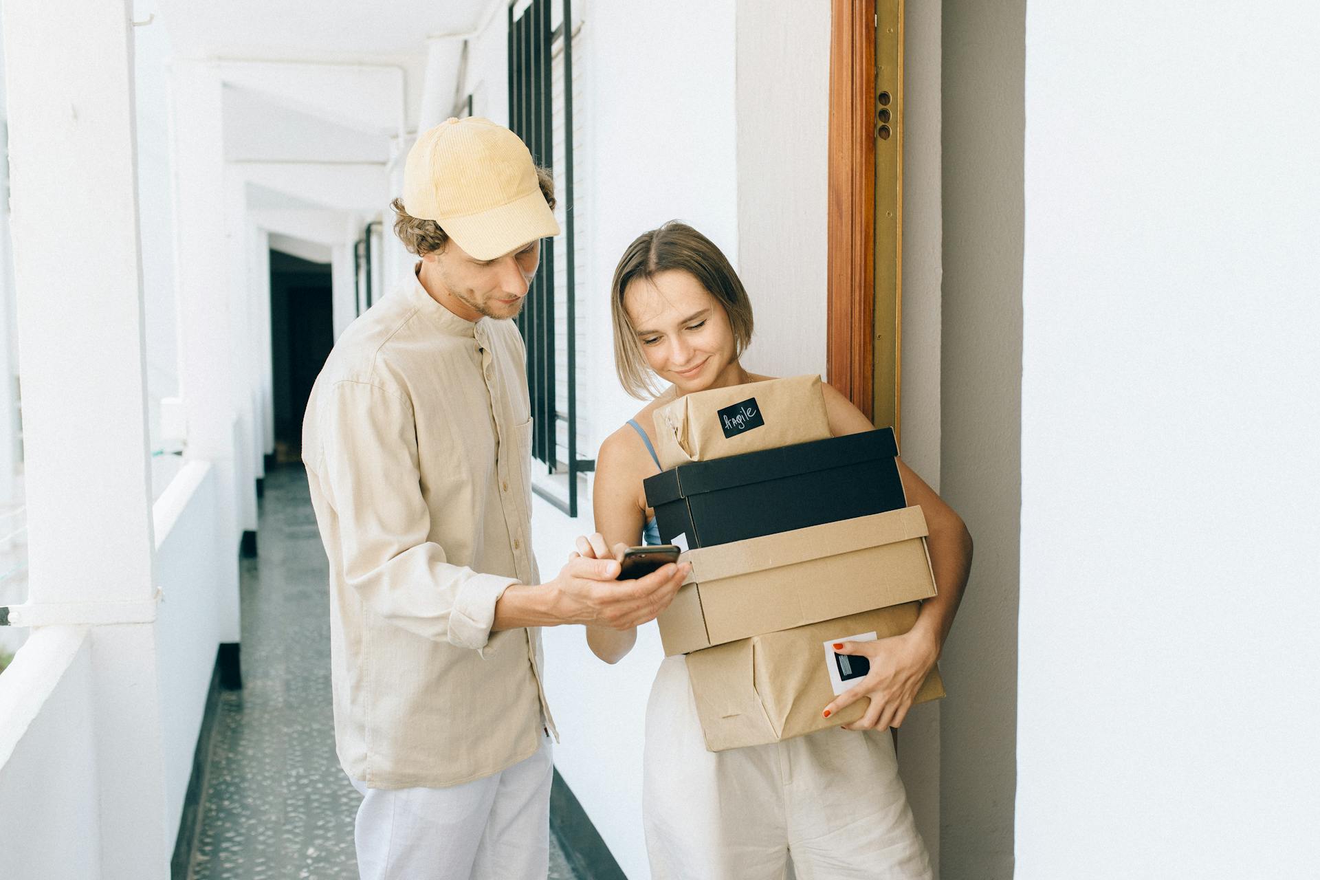 A man and woman holding boxes in a hallway.